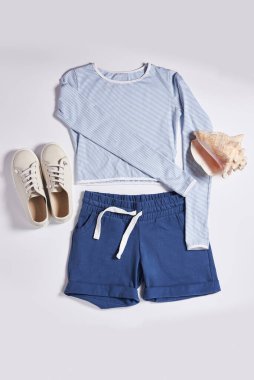 Pembe renkli atlet bluzu, şortu, uyumlu spor ayakkabısı ve beyaz arka planda metal bir taklacı da dahil olmak üzere şık bir spor kıyafetinin düz kompozisyonu. Fitness ve moda temaları için mükemmel