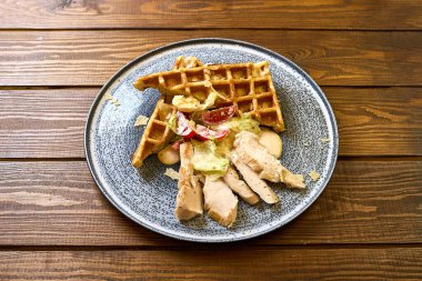 Izgara tavuk, kremalı Sezar salatası ve parmesan peynirli talaş ile kaplı çıtır bir waffle 'ın yer aldığı lezzetli bir yemek.