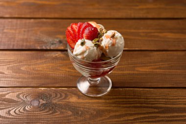 Üstüne taze çilek ve tatlı soslu klasik bir vanilyalı dondurma.