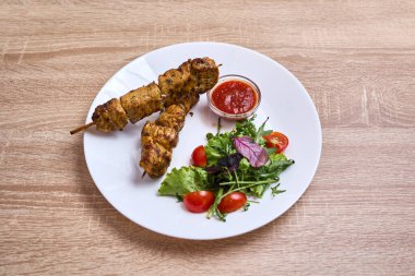 Taze salata ve sosla servis edilen yumuşak tavuk şişleri..
