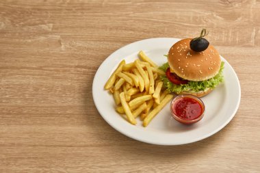 Kızarmış patates ve soslu leziz bir çizburger, beyaz tabakta servis edilir..