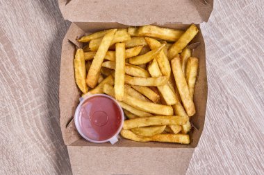 Karton bir kutuda ketçapla servis edilen kızarmış patates kızartması..