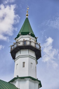 Bulutlu gökyüzüne karşı yeşil çatılı ve hilal aylı minare, İslami mimari ve kültürel miras kavramını sergiliyor