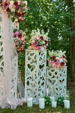 Açık hava bahçesinde yeşil yaprakların arasında beyaz kaidede pembe güller sergilenen sofistike çiçek desenleri, romantik dekor fikri.