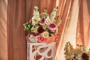 Şakayıklar, zambaklar, güller şeftali perdelerinin yanında durduğu doğal ışıkta zarif bir şekilde yerleştirilmiş çiçek düzenlemesi, estetik konsept