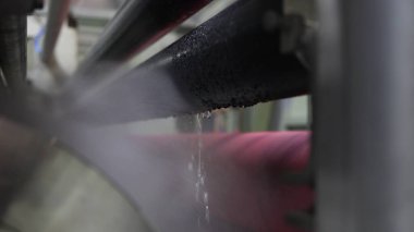 Tekstil üretim sürecinde metalden dökülen suyla endüstriyel makinelerin yakın çekimi, endüstriyel süreç kavramı