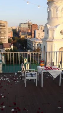 Gül yaprakları, sandalyeler, masa, gün batımı manzaralı romantik çatı yemek düzeneği, büyüleyici ortam konsepti