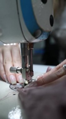 Makina çivileriyle dikiş dikerek kumaş işçiliği kavramını yaratan kadına yakın plan.