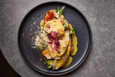 Taze sebzelerin, erimiş peynirin, zarif bir tabakta otlarla süslendiği gurme tavuklu sandviç, yakın çekim konsepti.