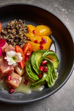 İçinde kinoa, avokado, ton balığı, nar tohumu, şeftali dilimleri, kiraz domatesleri, çiçek garnitürü, süper yiyecek çeşitleri, canlı ekran, sağlıklı beslenme fikri bulunan canlı bir kase.