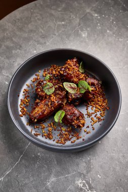 Lezzetli, soslu domuz pirzolası, soya salamurası ve kızarmış pirinç sosu. Koyu bir kâsede servis ediliyor. Zarif bir yemek.