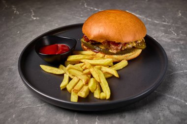 Kızartma, gurme burger, ketçap, siyah tabakta servis edilen iştah açıcı yemek sunumu, lezzetli yemek konsepti.