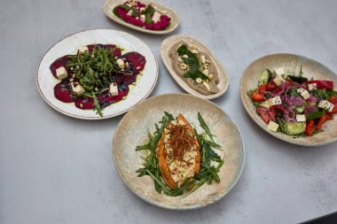 Salatalar, soslar ve tatlı patatesler de dahil olmak üzere sebzeli sebze yemekleri. Kırsal seramik tabaklara güzelce yerleştirilmiş..