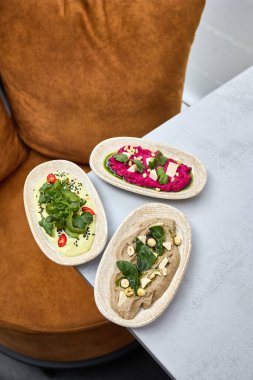 Taze otlar, fındıklar ve feta peyniri ile süslenmiş pancar, avokado ve mantarı içeren güzel kaplanmış bir humus çeşidi..