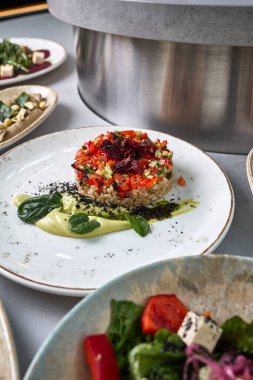 Tahıllardan ve doğranmış sebzelerden yapılmış, üzerinde çıtır pancar cipsi, avokado kreması ve taze yeşilliklerle servis edilen güzel bir vegan tartar..