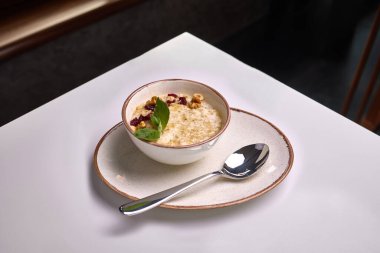 Cevizli yulaf ezmesi, kurutulmuş kızılcık ve seramik tabakta servis edilen taze nane yaprakları..