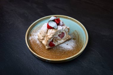 Zarif bir tatlı dilimi çilekli krema ile doldurulmuş taze çilek ve pudra şekerle süslenmiş..