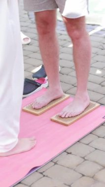 Çıplak ayakla çivi tahtasında duran bir adam. Sağlıklı yaşam süresince ya da acı dayanıklılık seansında. Pembe yoga minderinde..