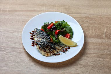 Soslu ızgara uskumru tabağı, yanında vişneli domatesli taze salata ve limonlu garnitür..