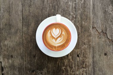 Ahşap arka planda bir fincan latte sanat kahvesi.                                                                                                                                                                     