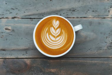 Ahşap arka planda bir fincan latte sanat kahvesi.                                                                                                                                                                                           