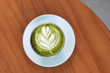 Bir fincan yeşil çay, ahşap arka planda matcha latte.                                                                                                                                                                                          