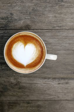 Ahşap arka planda bir fincan latte sanat kahvesi.                                                                                                                                                                                                            