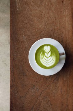 Bir fincan yeşil çay, ahşap arka planda matcha latte.                                                                                                                                                                                          