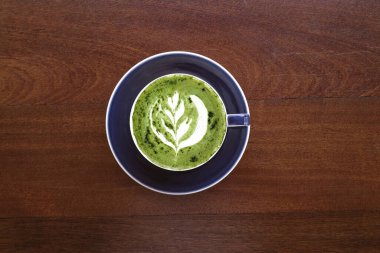 Bir fincan yeşil çay, ahşap arka planda matcha latte.                                                                                                                                                                                          
