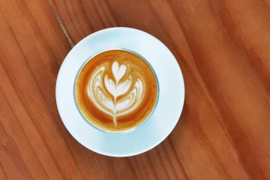 Ahşap arka planda bir fincan latte sanat kahvesi.                                                                                                                                                                                           
