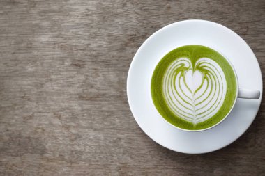 Bir fincan yeşil çay, ahşap arka planda matcha latte.                                                                                                                                                                                          