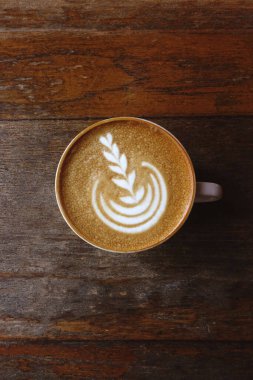 Ahşap arka planda bir fincan latte sanat kahvesi.                                                                                                                    