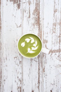 Bir fincan yeşil çay, ahşap arka planda matcha latte.                                                                                                                                                                                          