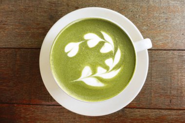 Bir fincan yeşil çay, ahşap arka planda matcha latte.                                                                                                                                                                                          