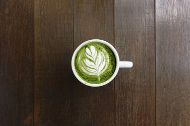 Bir fincan yeşil çay, ahşap arka planda matcha latte.                                                                                                                                                                                          