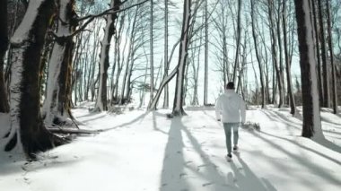 Çocuk kışın ağaçla karlı dağda yürüyor.