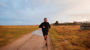 Kulaklıklı bir adam yağmur günü dışarıda koşuyor..