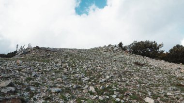 Kuru bir dağın tepesinde taşlar ve gri topraklar.