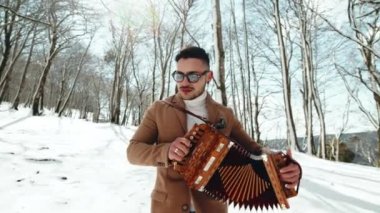 Çocuk tipik Calabria enstrümanı akordeon ve müzik tarantellasını karla birlikte dağda çalıyor.