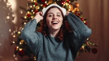 Kız Noel şapkasını ağaca dayıyor..