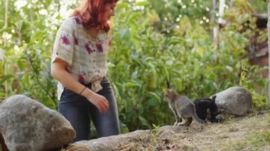 Kız kırsaldaki bahçesinde evcil kediyle oynuyor.