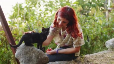 Kız kırsaldaki bahçesinde evcil kediyle oynuyor.