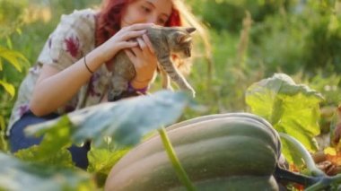 Kız kırsaldaki bahçesinde evcil kediyle oynuyor.