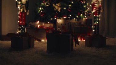 Parlayan ışıkları olan beyaz halıda üç Noel hediyesi kutusu..