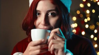 Kız Noel ağacına karşı bir fincan sıcak çikolata içiyor..