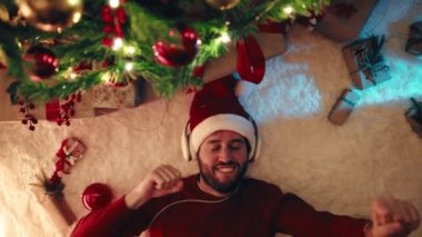 Mutlu adam Noel ağacının altında müzik dinliyor..