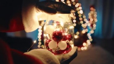 Noel Baba elinde Noel süsleriyle bir kavanoz tutuyor..
