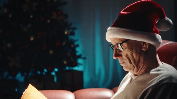 Elderly Man Reading Book Christmas Sofa House — Stock Video