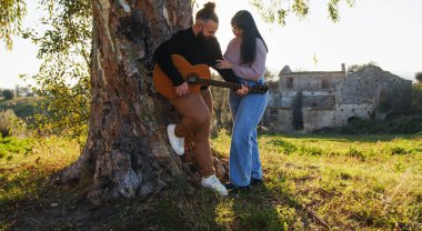 Sevgililer günü için ağacın altında gitar çalan çift..