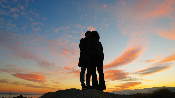 Silhouette of couple hug against the sunset sky.
